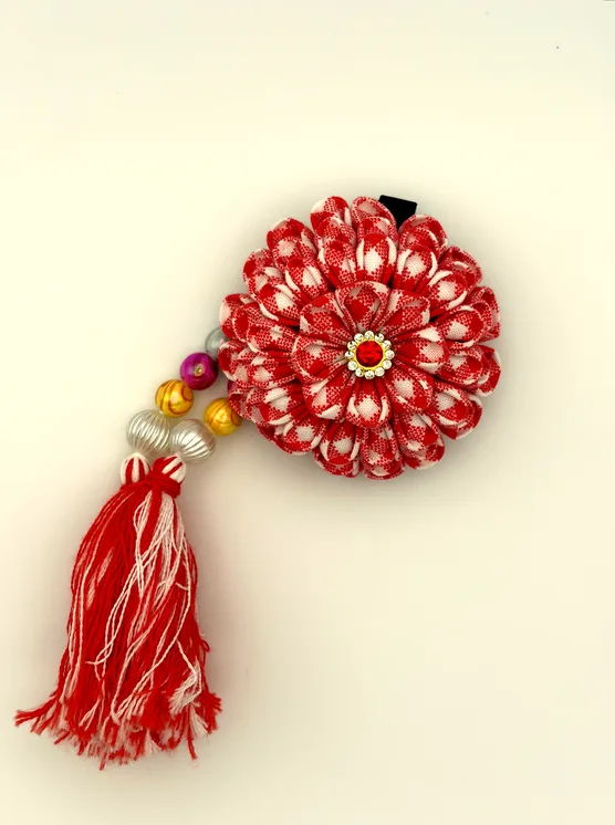 赤白格子の花びらに赤いラインストーンを添えた一輪。紅白の房飾りで華やかに。