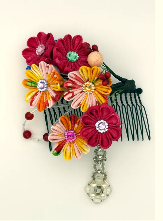 赤・ピンク・オレンジの花々に木製ビーズを添え、揺れるパール付きチャームが華やぐヘアコームです。